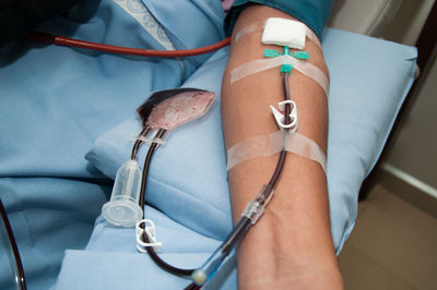 Cropped hand of patient with iv drip on bed