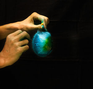 Close-up of man holding hand over black background