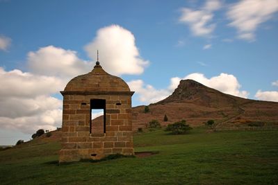 Built structure on field against cloudy sky