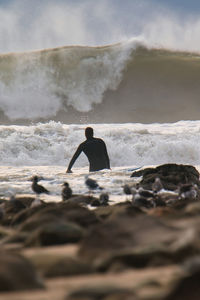 Rear view of man in sea against sky