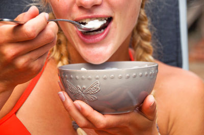 Midsection of young woman eating food from bowl
