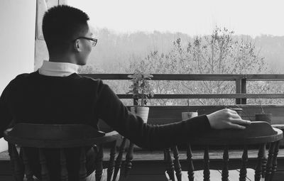 Rear view of young man sitting on chair at restaurant