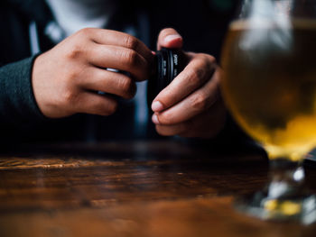 Close-up of hand holding drink on table