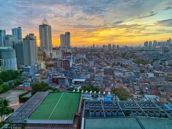 Aerial view of buildings in city against sky during sunset