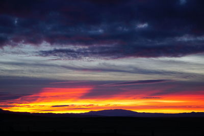 Silhouette landscape against dramatic sky during sunset