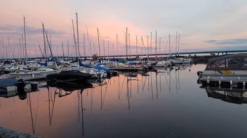 Sailboats moored on sea against sky during sunset