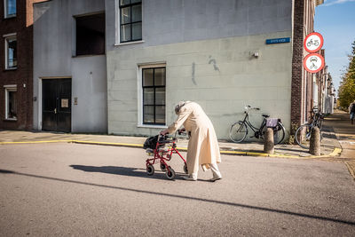 Man riding bicycle on road against building