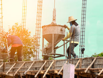 Rear view of people working at construction site against sky