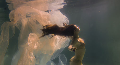 Woman with curtain swimming in pool