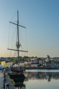 Sailboats moored at harbor against sky during sunset