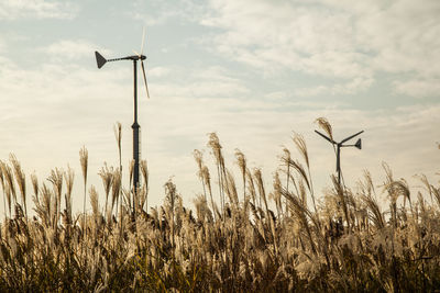 Wind turbines on field against cloudy sky