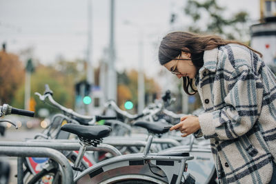 Young woman unlocking bicycle through smart phone