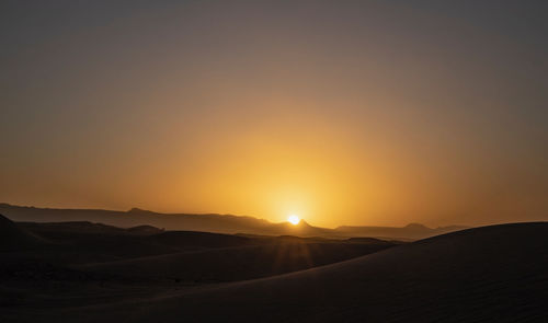 Scenic view of desert against sky during sunset