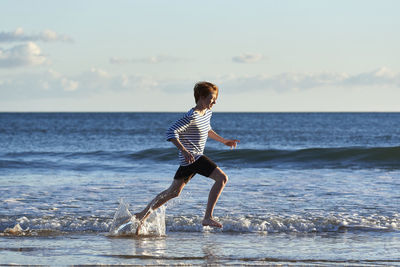 Full length of boy on beach against sky