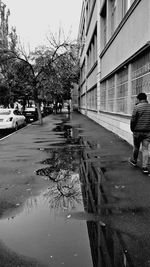 Rear view of man walking on wet road