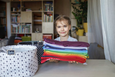 Portrait of smiling girl holding clothes at home