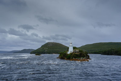 Lighthouse by sea against sky