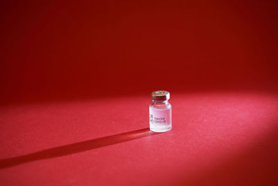 Close-up of bottle on table against red background