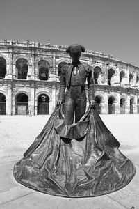 Man walking in front of historical building against clear sky