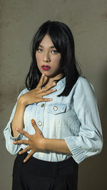 Portrait of beautiful young woman standing against wall