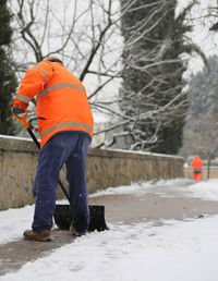 Man working on snow covered tree
