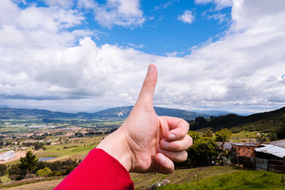 Person showing thumbs up against sky