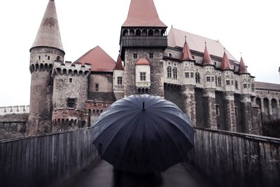 Person with umbrella against historic building