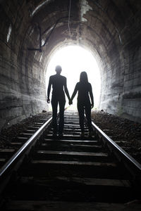 Rear view of silhouette people walking in tunnel