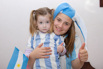 Portrait of sisters with argentinian flag against wall