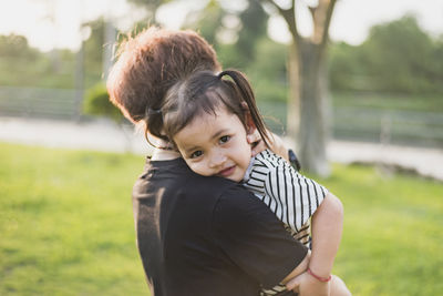 Side view of mother carrying daughter at park