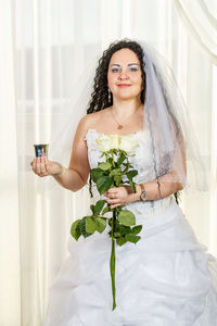Young woman holding flower bouquet against white wall
