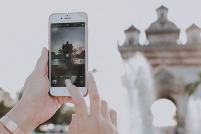 Person photographing historic building with mobile phone