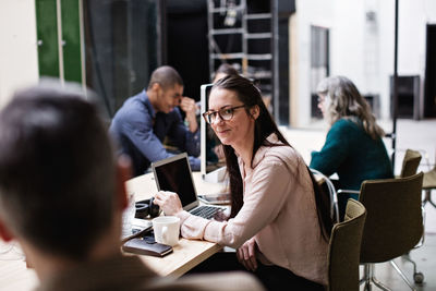 Male and female business colleagues discussing in meeting at table in creative office