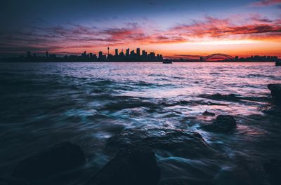 Scenic view of seascape by city during sunset