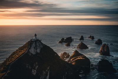 Panoramic view of rocks on sea against sky during sunset