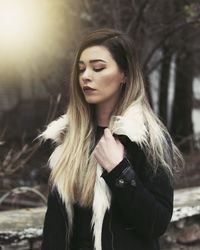 Young woman holding jacket against trees in forest