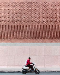 Man riding bicycle on brick wall