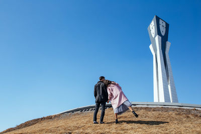 Low angle view of person against clear blue sky