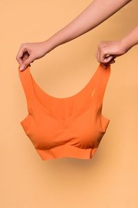 Midsection of woman holding orange against gray background