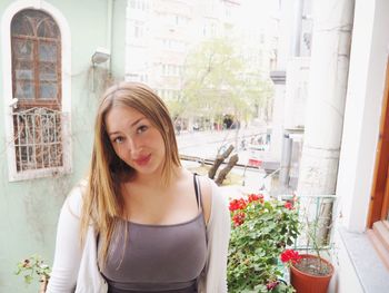 Portrait of smiling young woman against plants