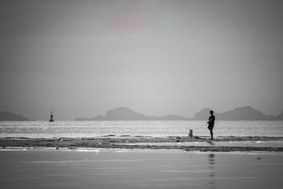 Silhouette people on beach against clear sky