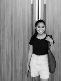 Portrait of a smiling girl standing against wall