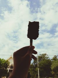 Person holding ice cream cone against sky