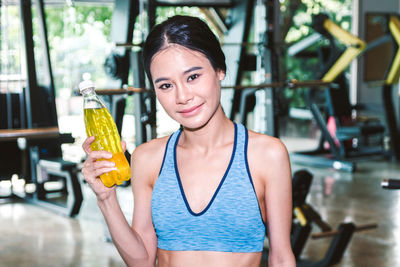 Portrait of woman holding drink in bottle at gym