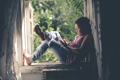 Kid girl on the box with the phone, the concept of sadness and loneliness, problems with gadgets