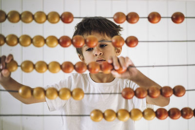 Boy learning to count using abacus in classroom at kindergarten