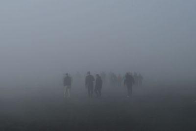 People walking on snow covered landscape against sky