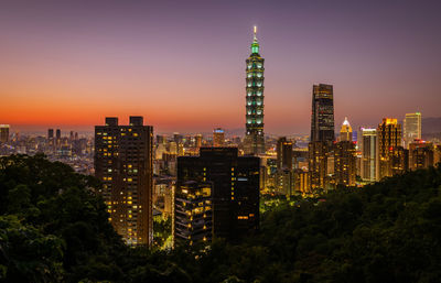 Aerial view of illuminated buildings in city at dusk
