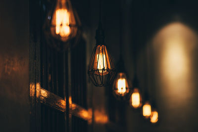 Close-up of illuminated light bulb hanging at night