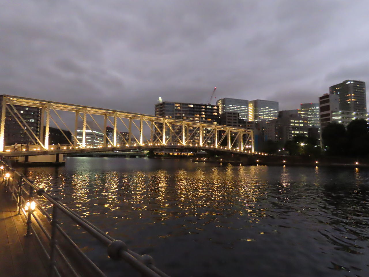 ILLUMINATED BRIDGE OVER RIVER AGAINST SKY IN CITY